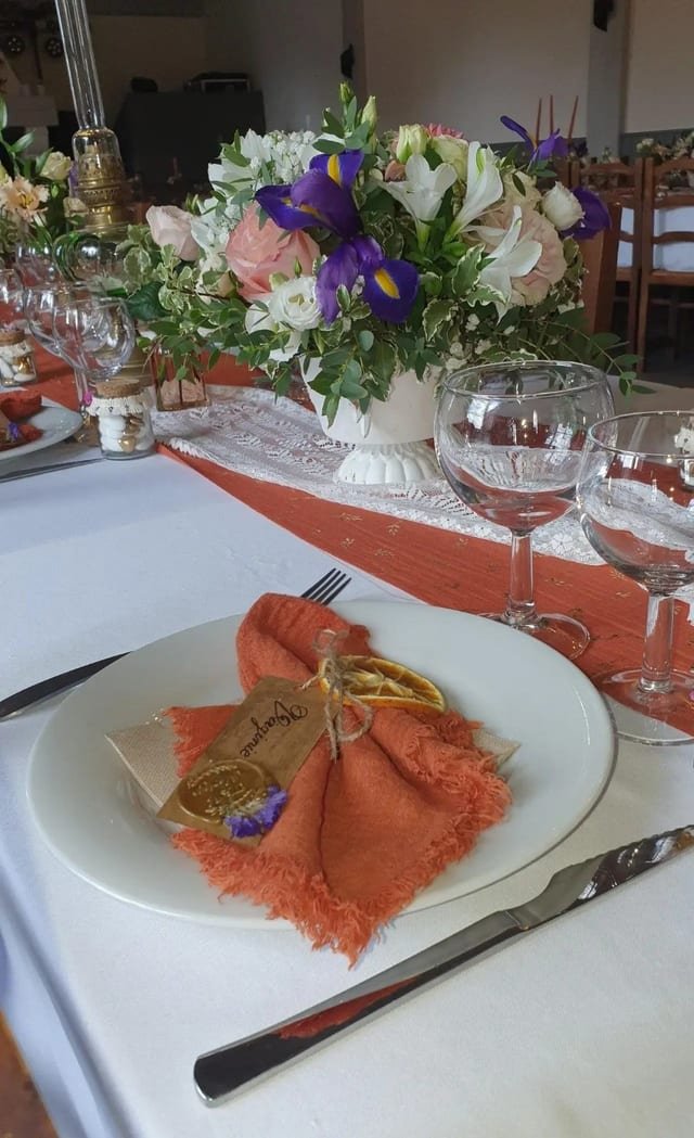 Marque-place en kraft posé sur une serviette terracotta, avec une rondelle d’orange séchée