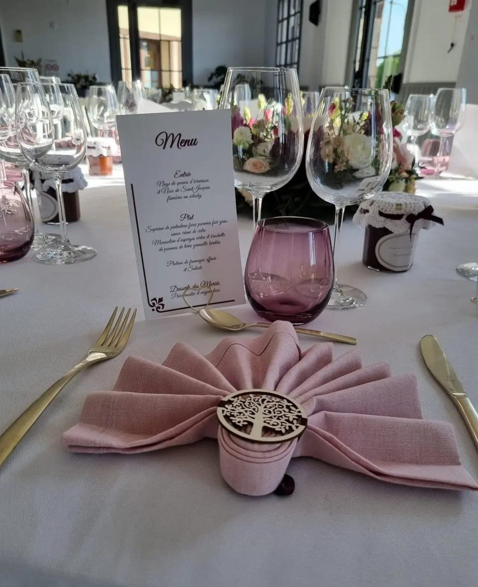 Couvert dressé avec menu, serviette rose poudré et couverts dorés